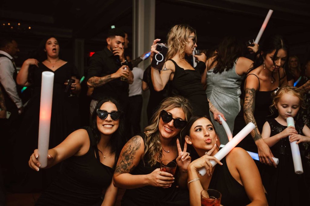 Guests in sunglasses with light sticks at marquee events wedding